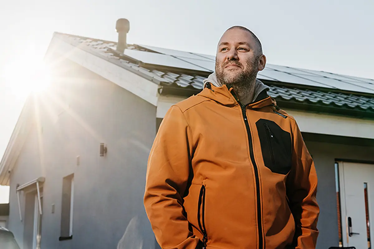 Glad man på bild framför solpaneler