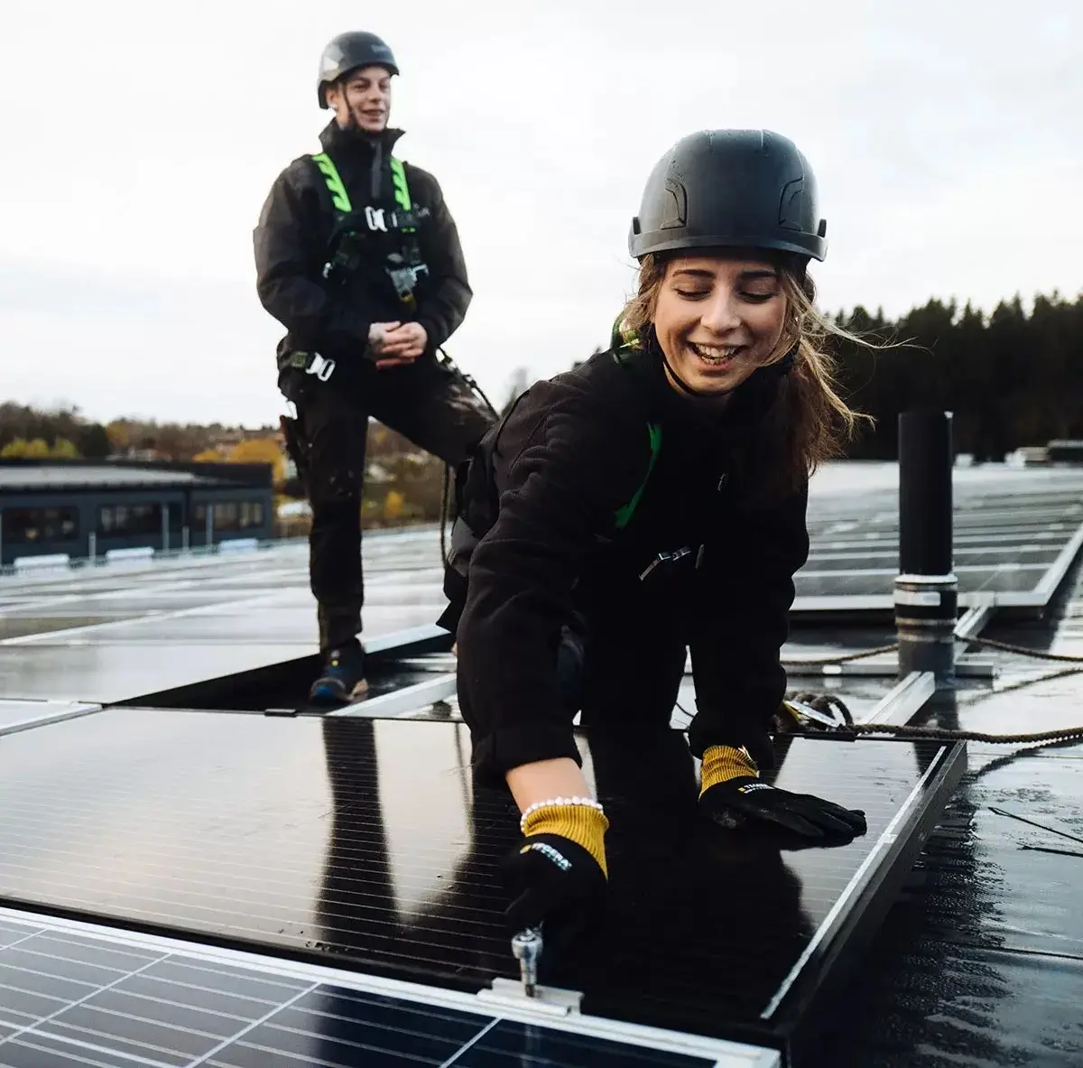 Två installatörer som installerar solceller på ett tak