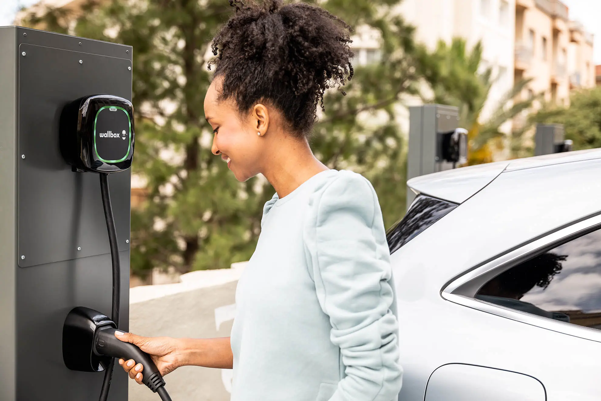 Frau lädt E-Auto an Wallbox auf.