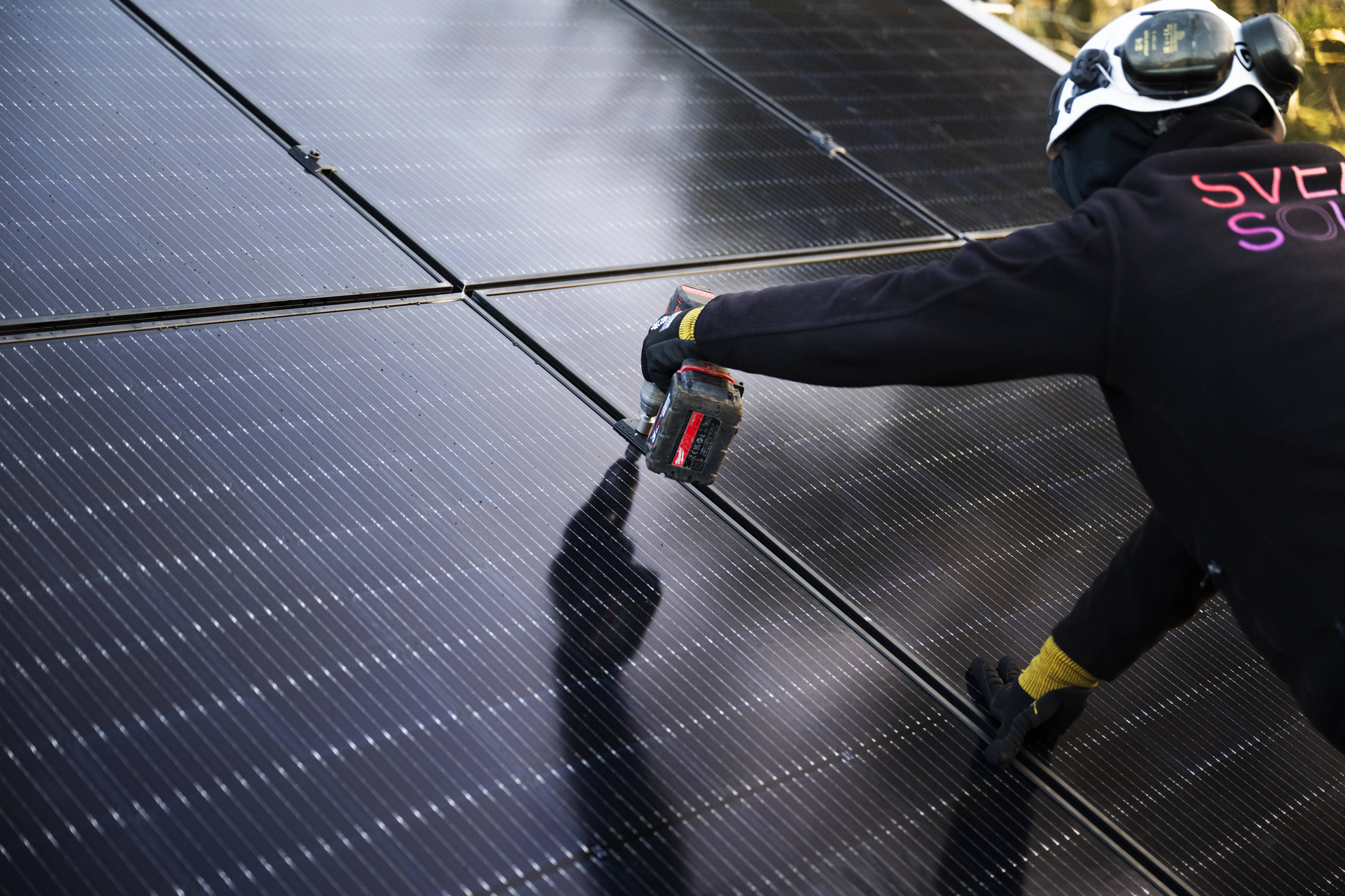 Un installateur de Svea Solar pose des panneaux solaires sur un toit.