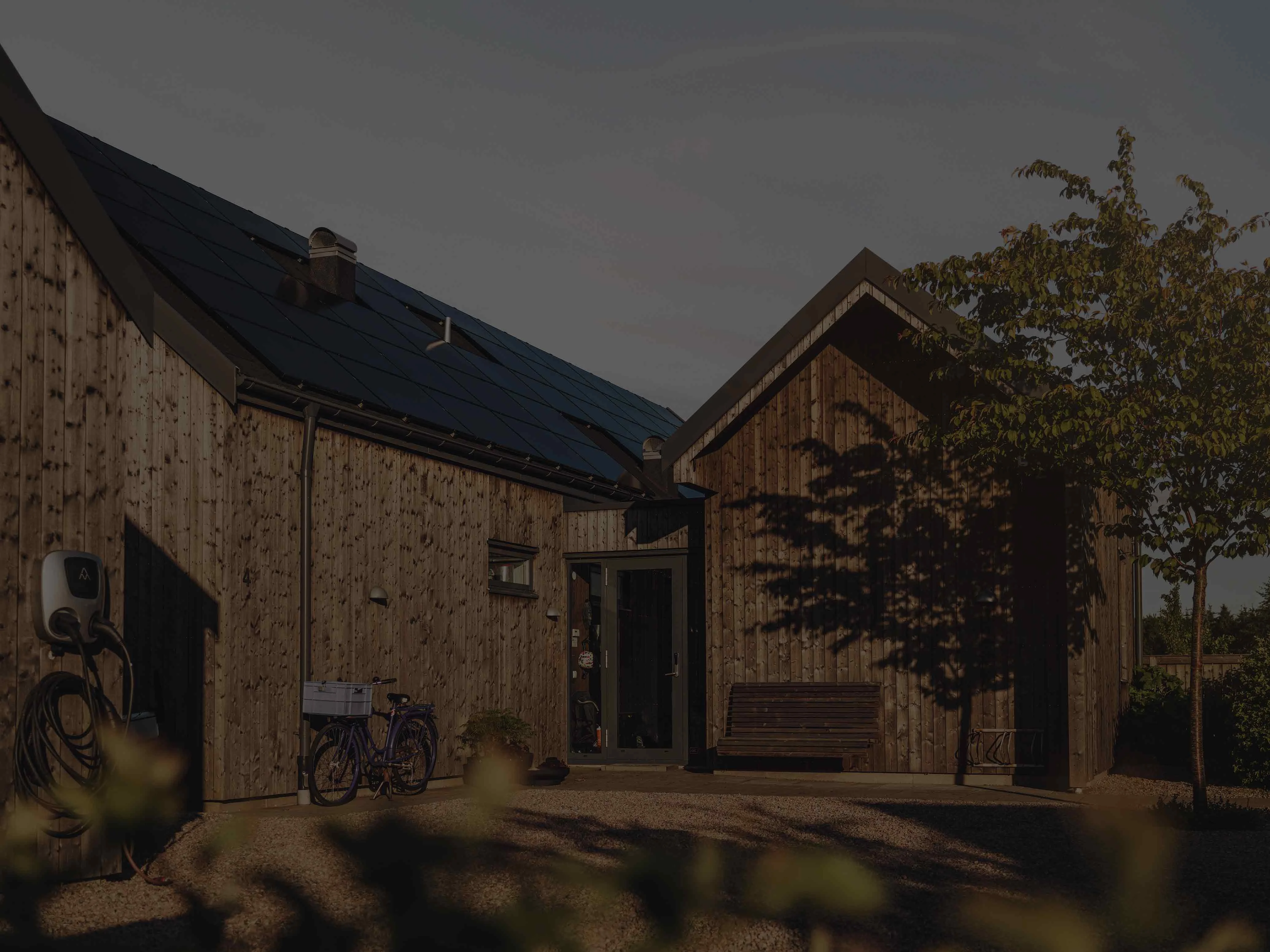 Holzhaus mit Solarpaneelen auf dem Dach und einer Wallbox
