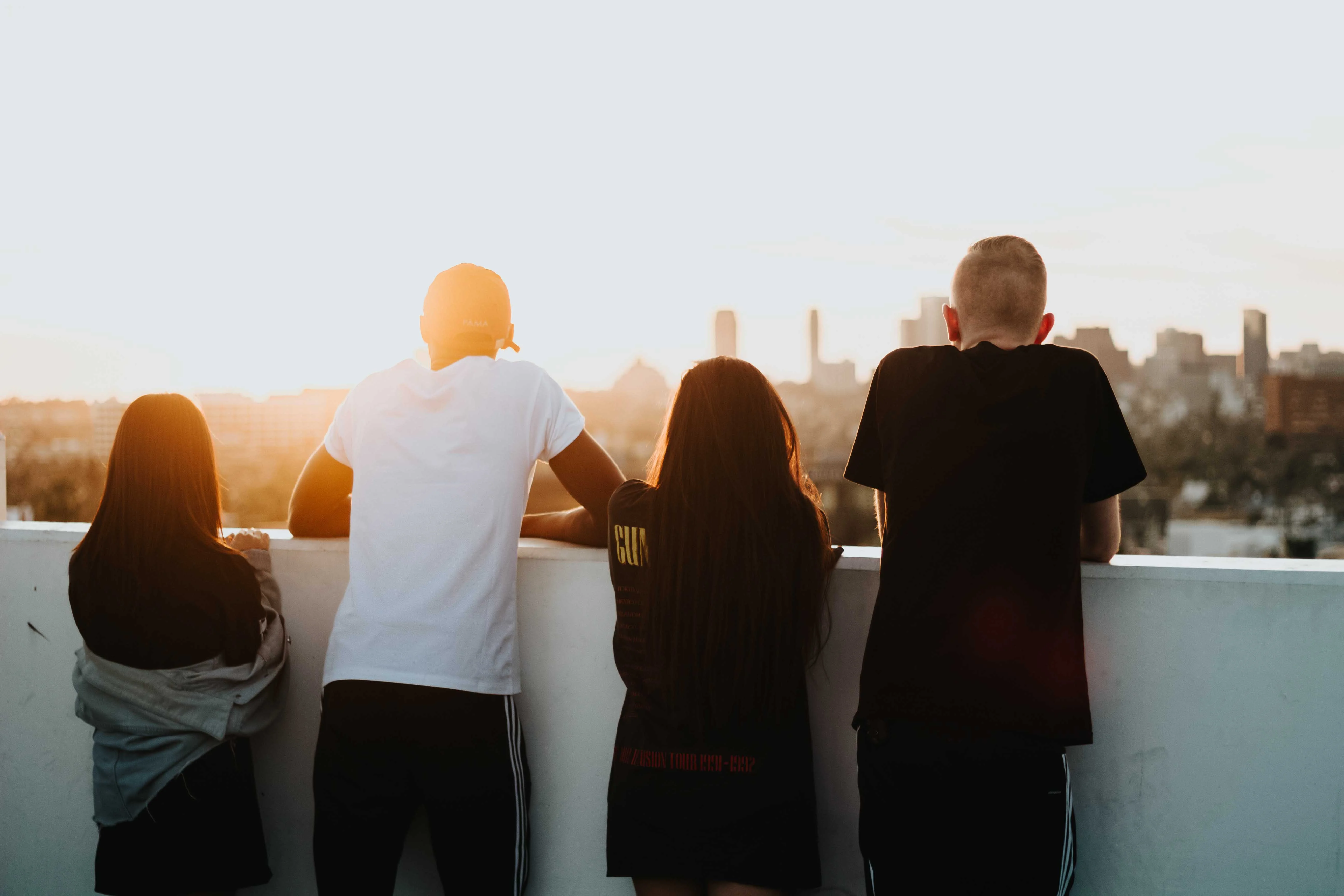 Gruppe junger Menschen schauen von einem Gebäude auf die Stadt bei Sonnenuntergang. (Stipendium)