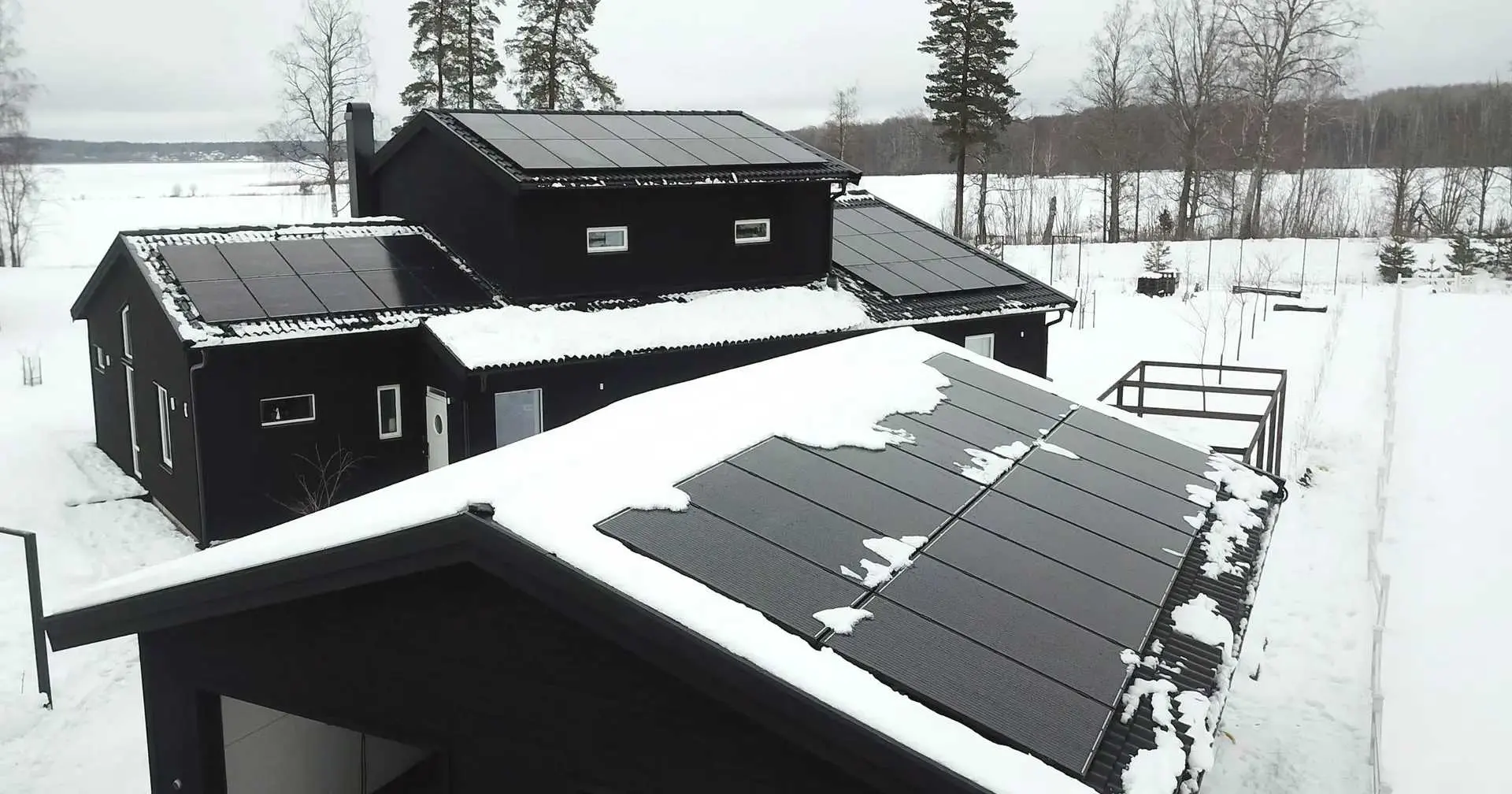 Schneebedecktes Dach mit Solaranlagen.