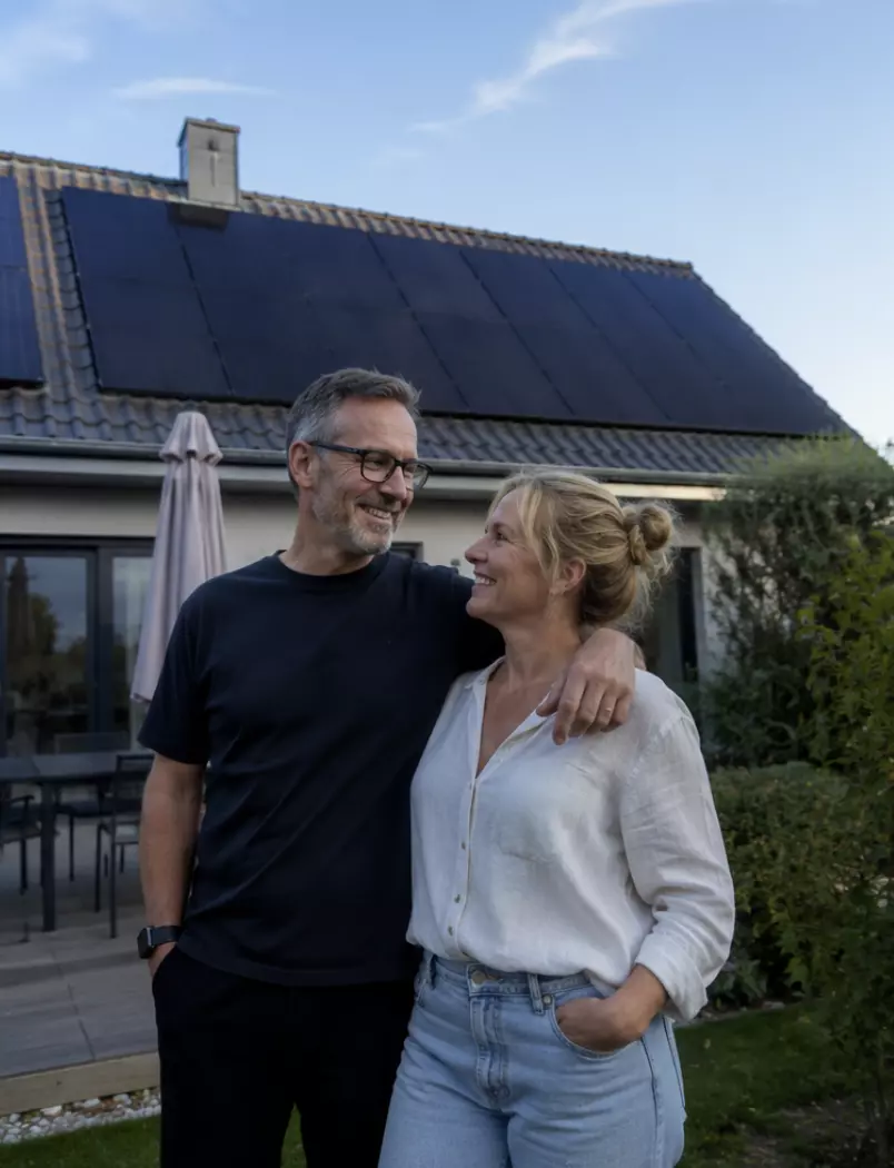 Paar vor Einfamilienhaus mit Photovoltaikanlage auf dem Dach – eigener Solarstrom für ein nachhaltiges Zuhause
